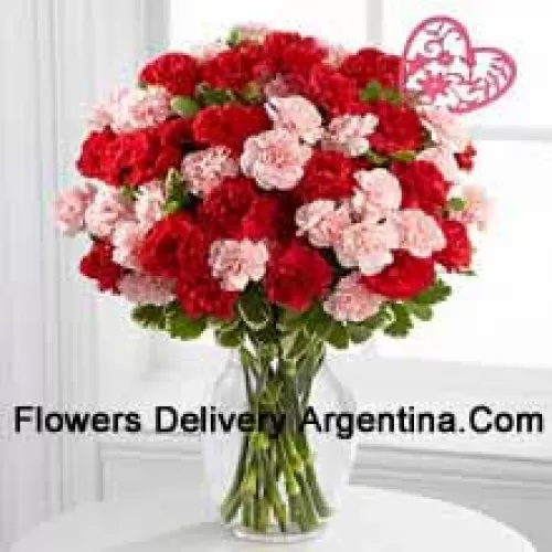 37 Oeillets (19 rouges et 18 roses) avec des remplissages saisonniers et un bâton en forme de cœur dans un vase en verre